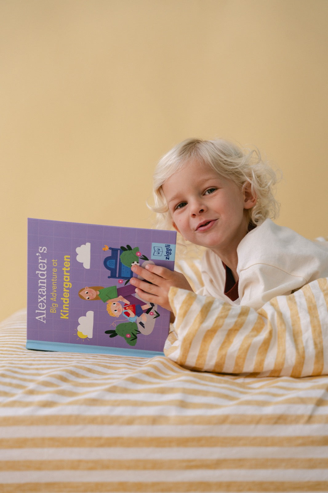 Boy smiling and holding his personalised Big Adventure book in bed