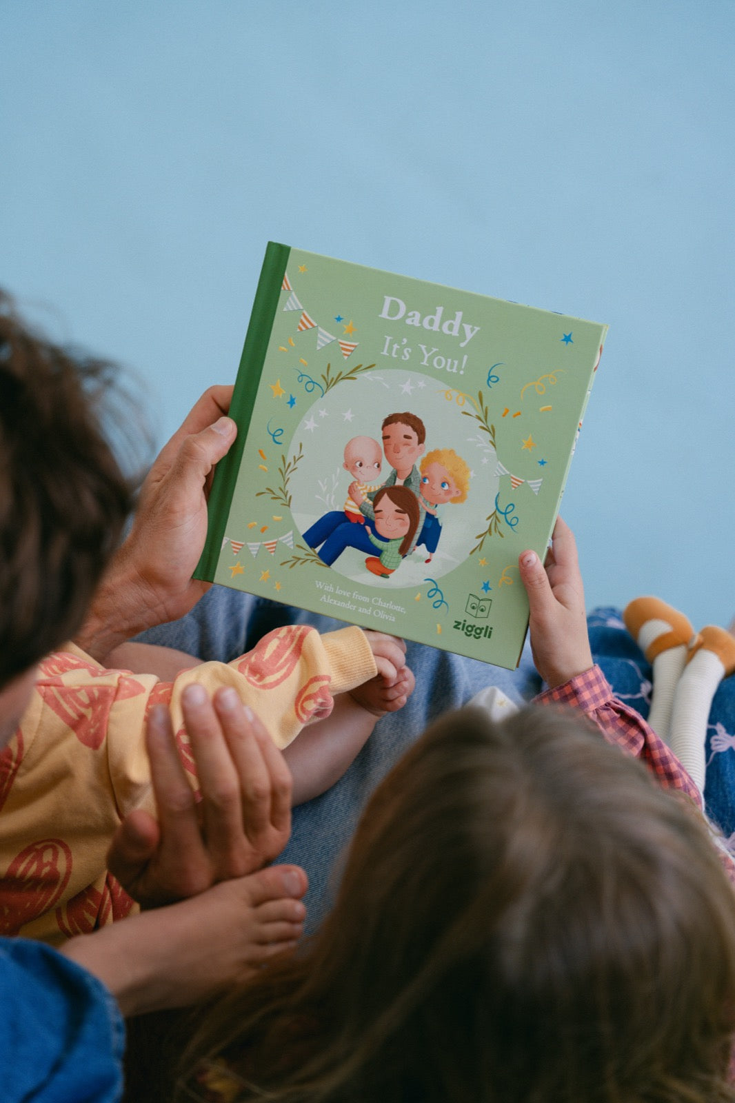 Daddy It's You personalised book cover held by dad with kids' feet visible