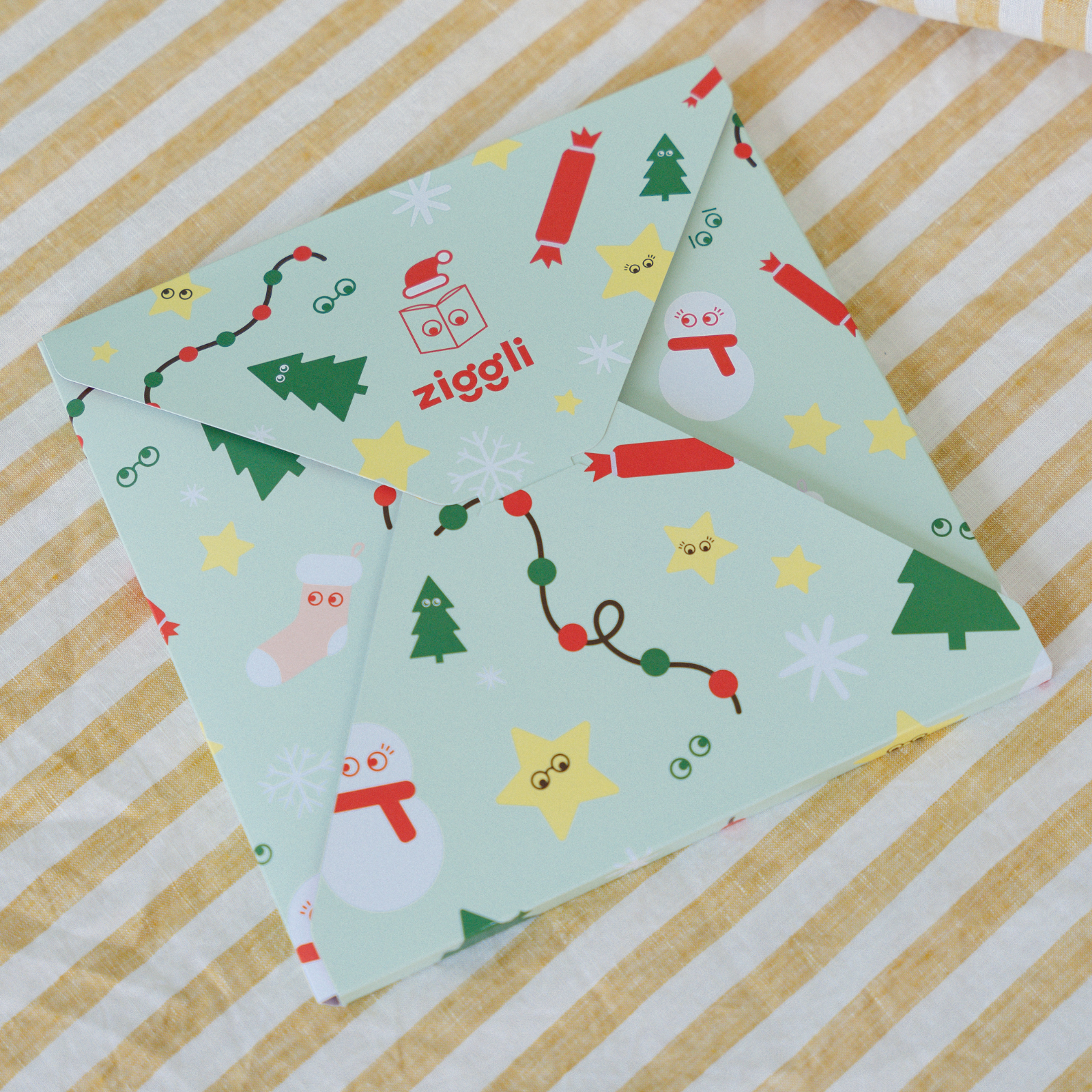Colourful patterned personalised book christmas gift wrap with 'ziggli' branding on a striped beige background