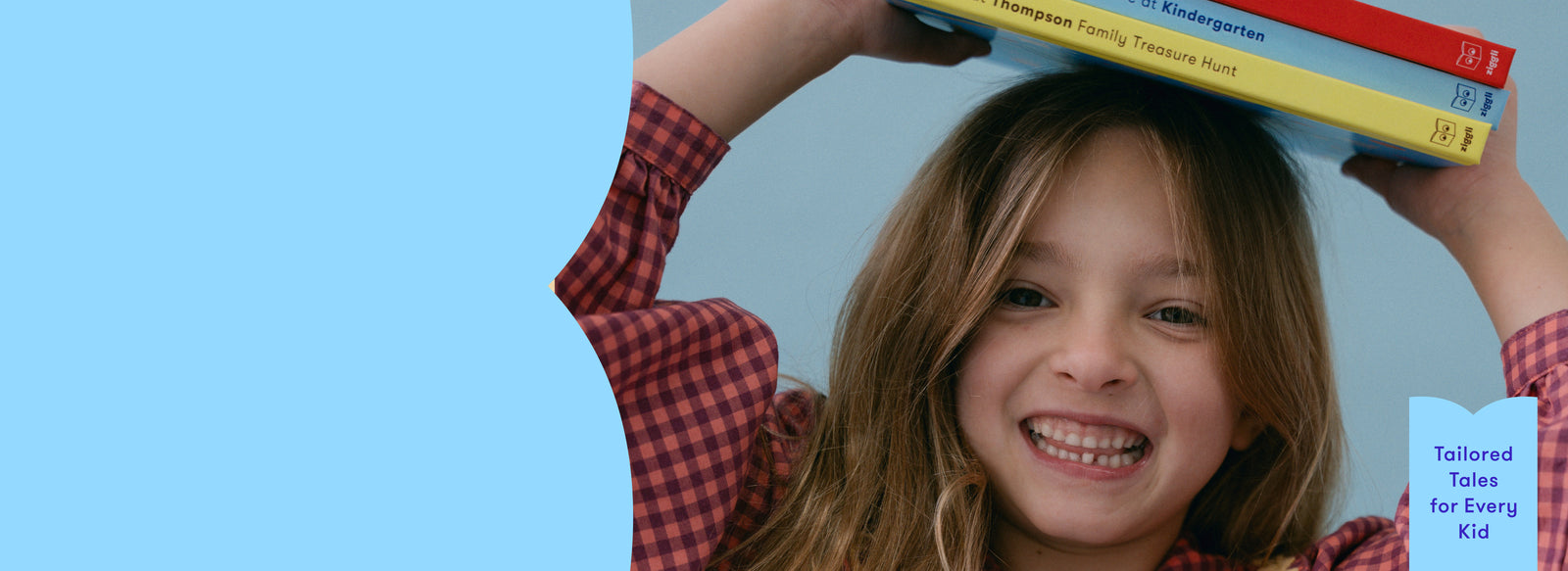 Child holding personalised books above their head with a blue background
