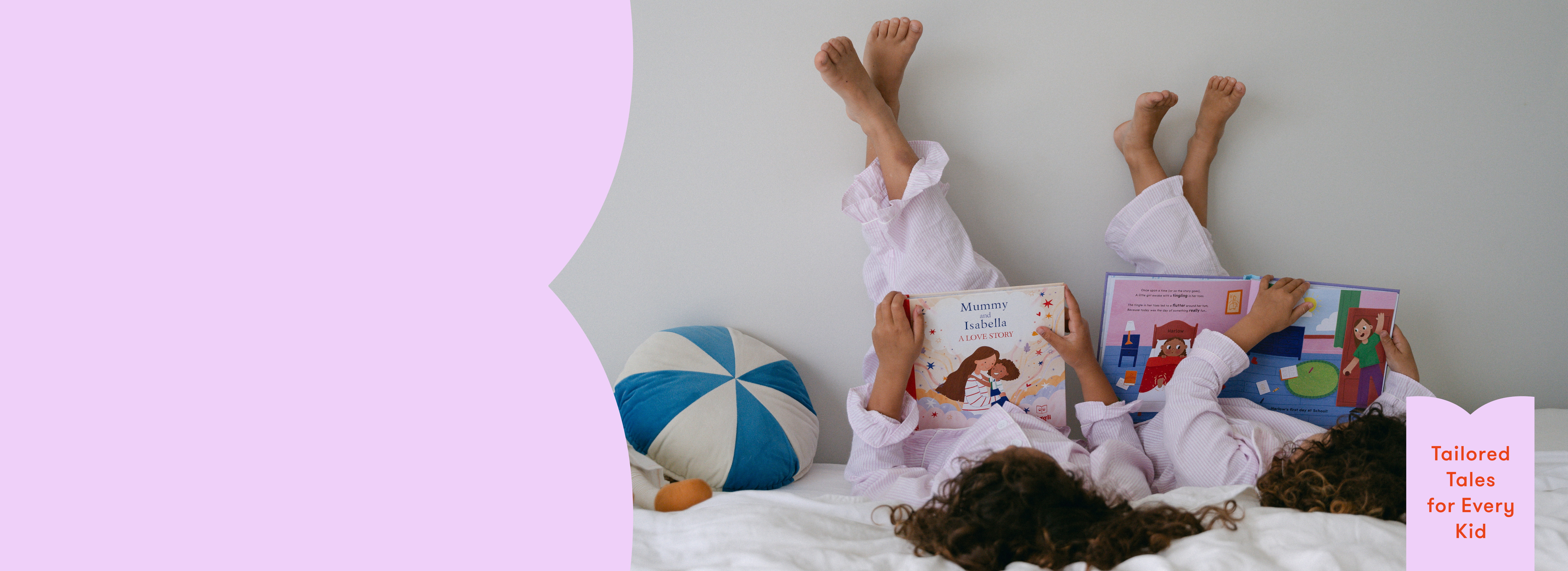 Two children lying on a bed reading personalised books with a colourful pillow and light purple wall in the background.
